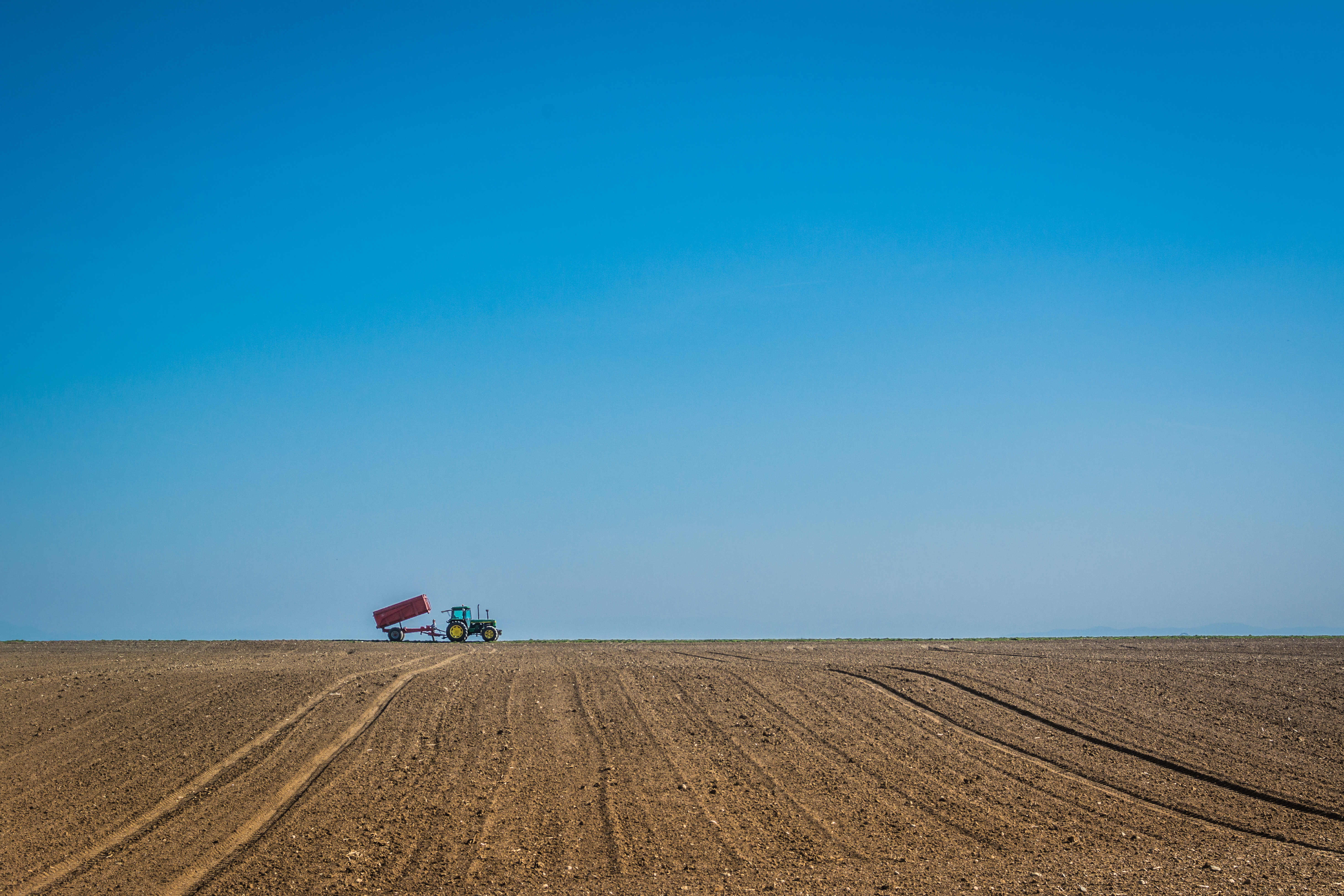 Tractor on arable land and clear sky as background